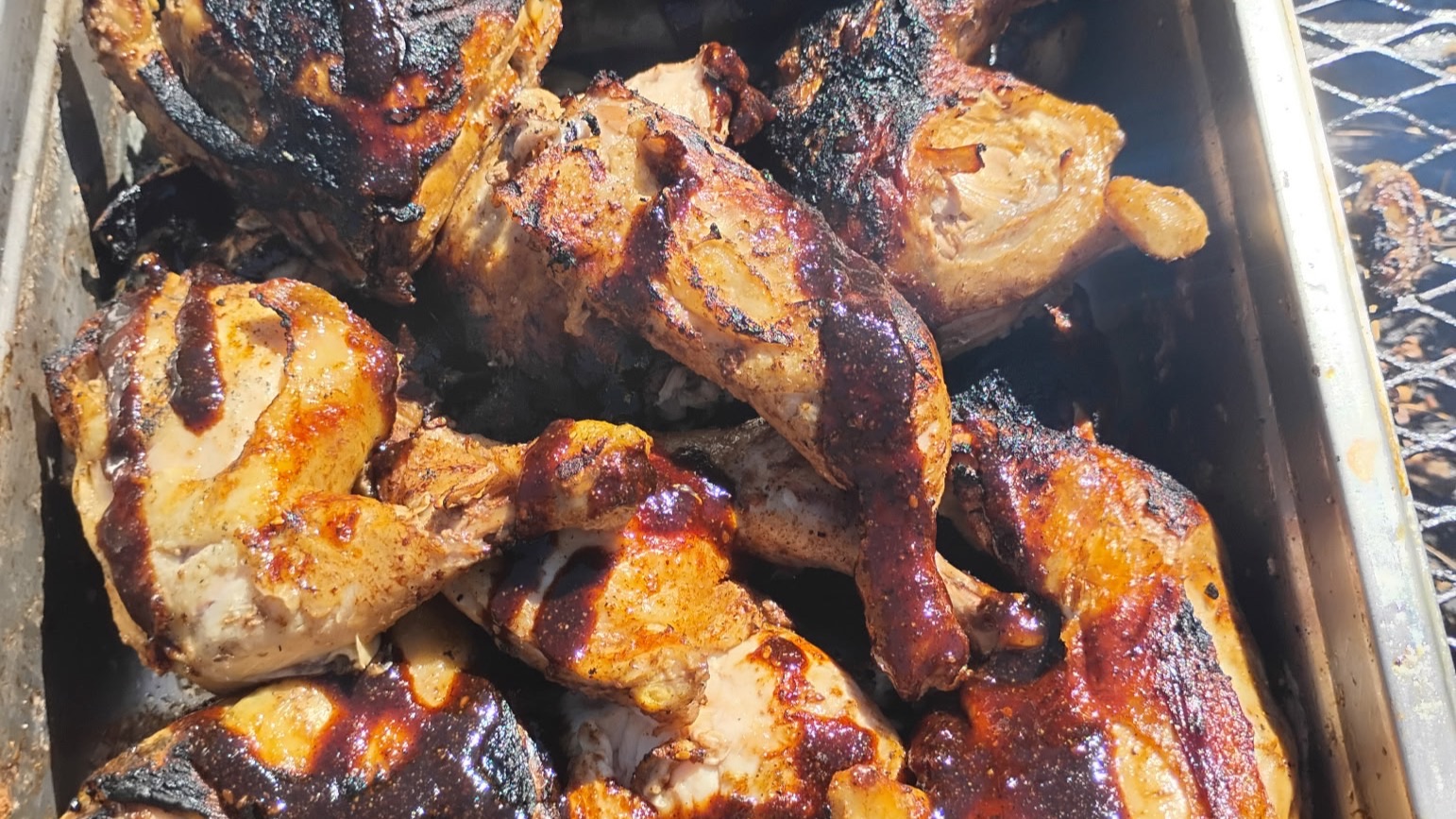 Grilled BBQ chicken in a steel pan on the grill